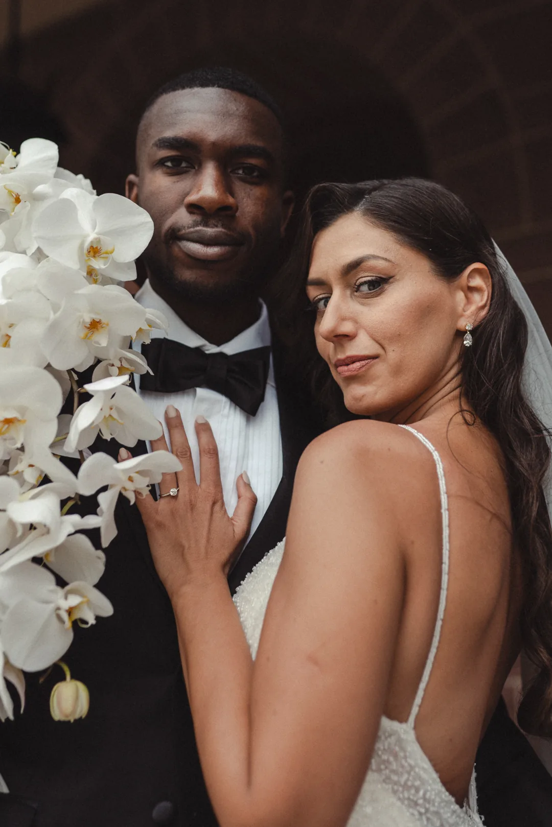 Couple posing with white orchids on their wedding day