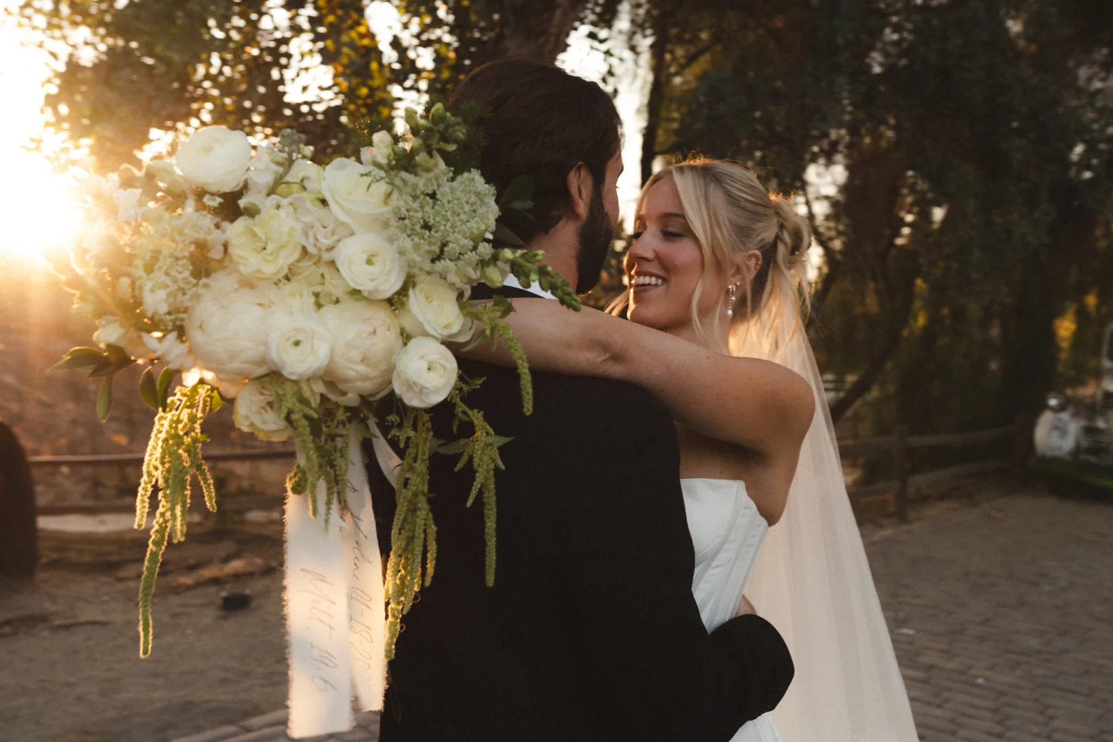 Couple embracing with a bouquet in golden evening light