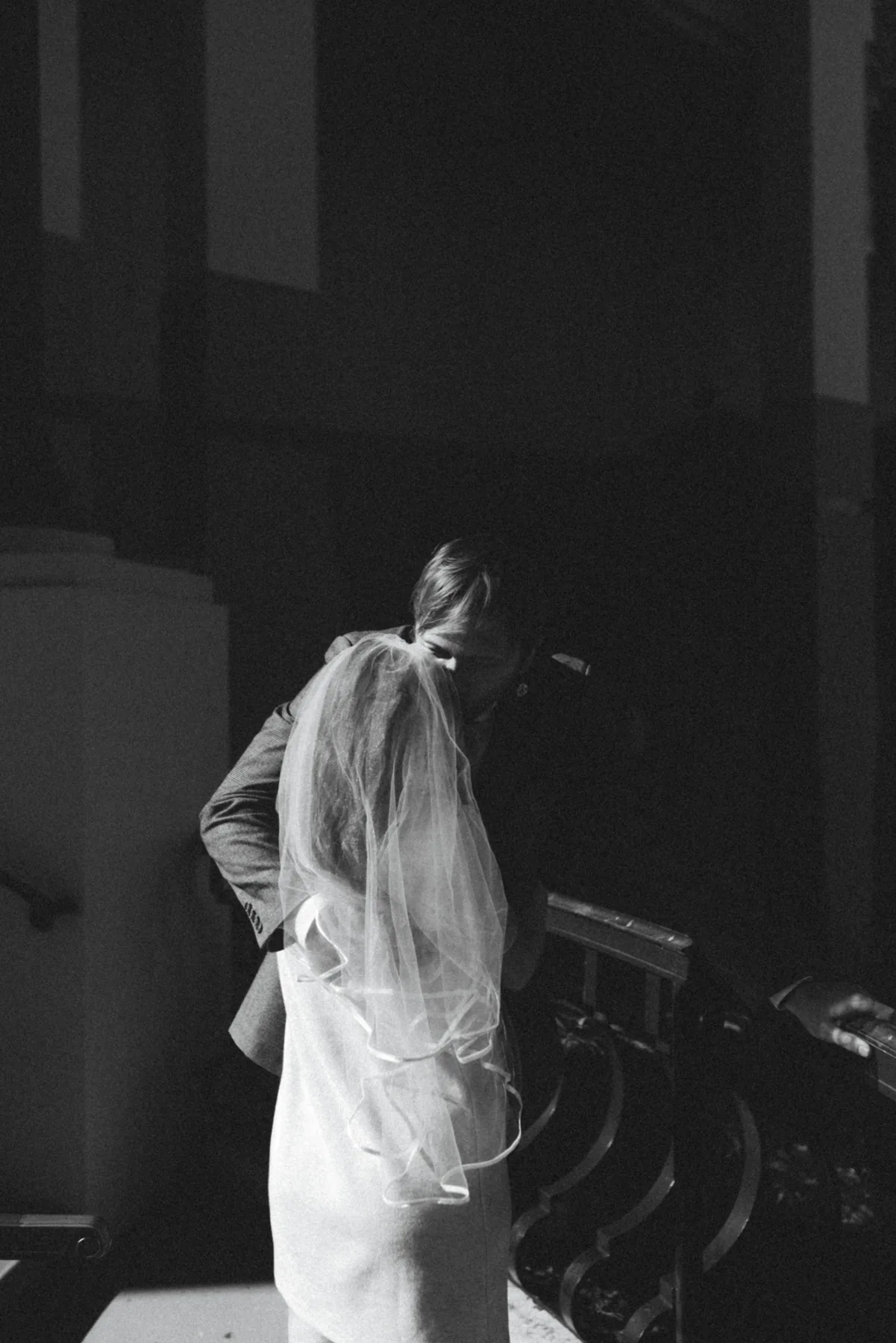 Bride in a veil descending a shadowed staircase