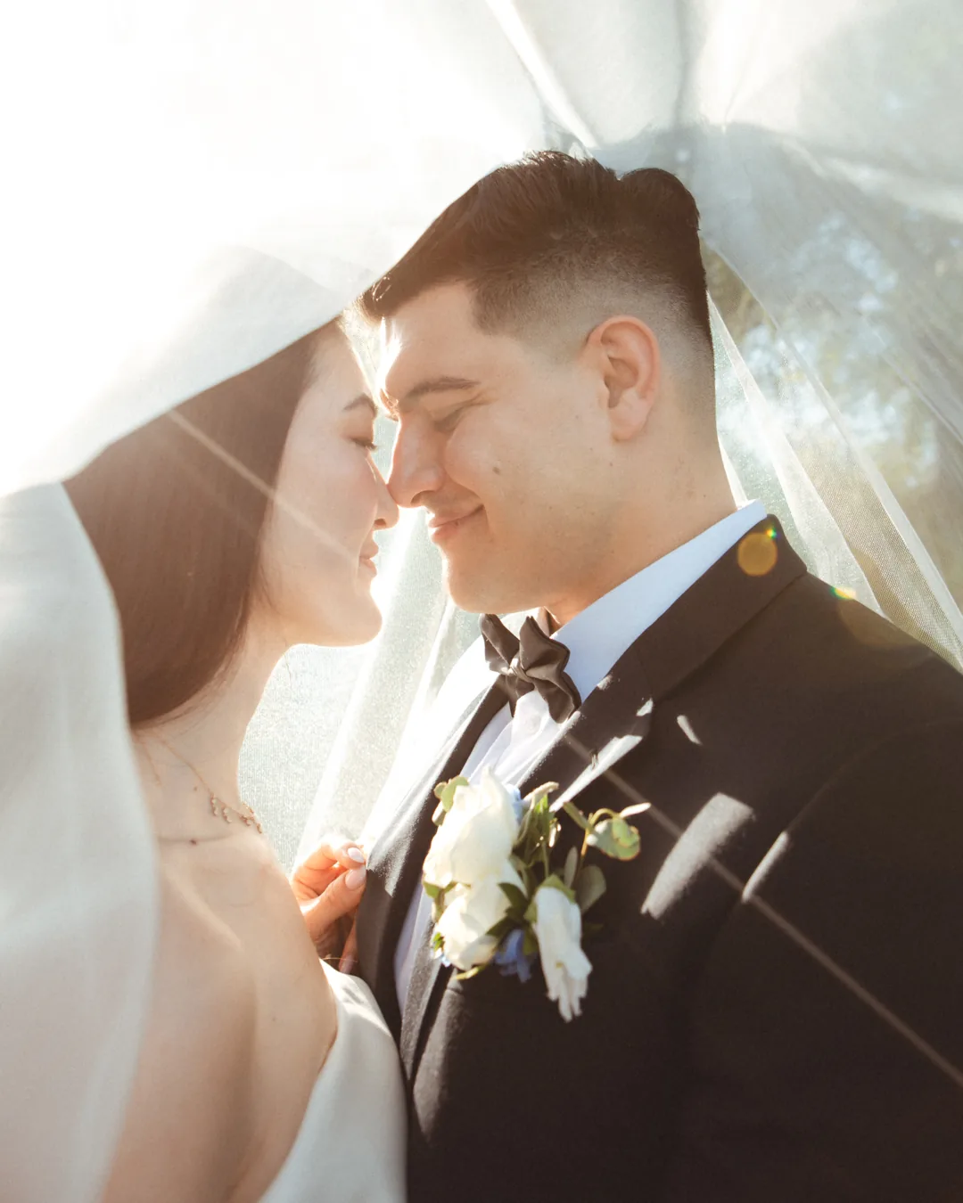Couple smiling together beneath a veil